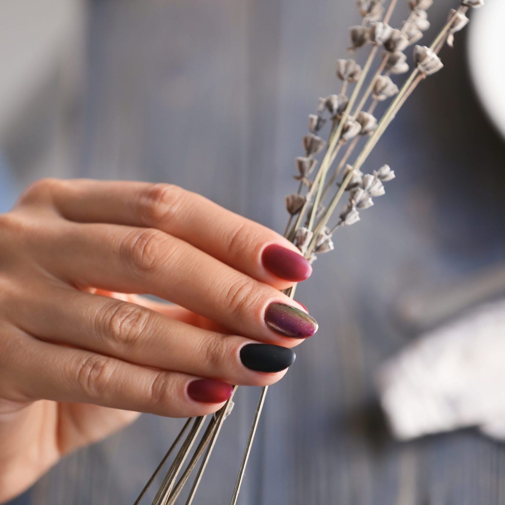 Woman with stylish beautiful manicure holding flowers, closeup